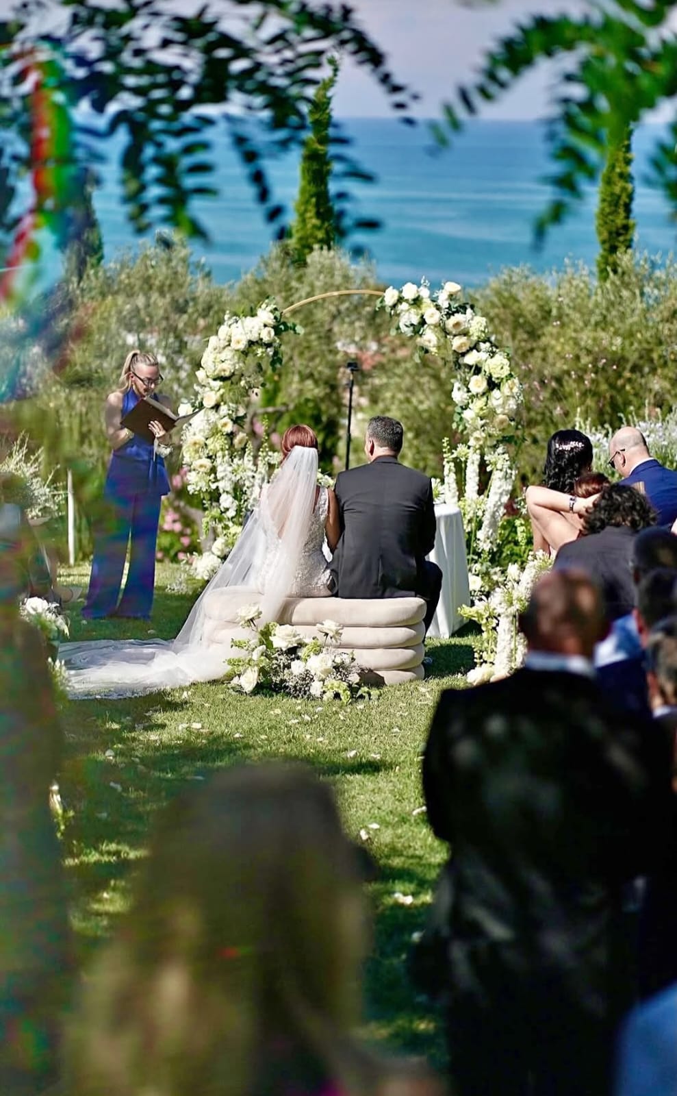 Cerimonia di matrimonio all'aperto con arco floreale e vista mare